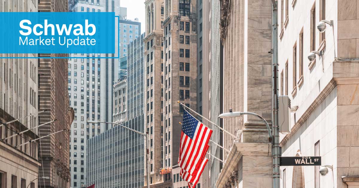 Schwab Market Update: A view of buildings and American flags on Wall Street.