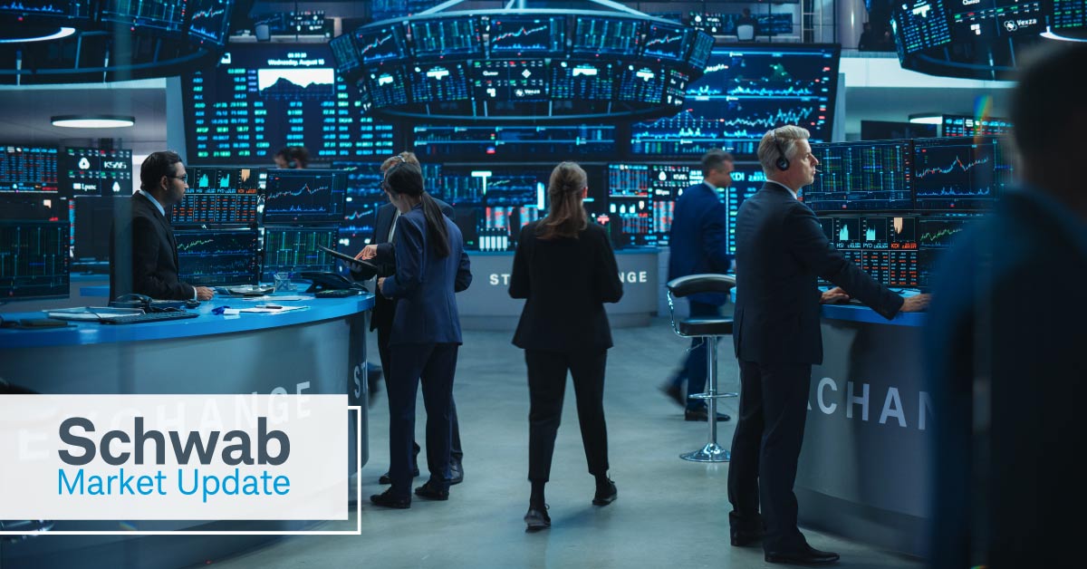 Schwab Market Update: Stock exchange trader work together in an office, surrounded by screens and large charts. 