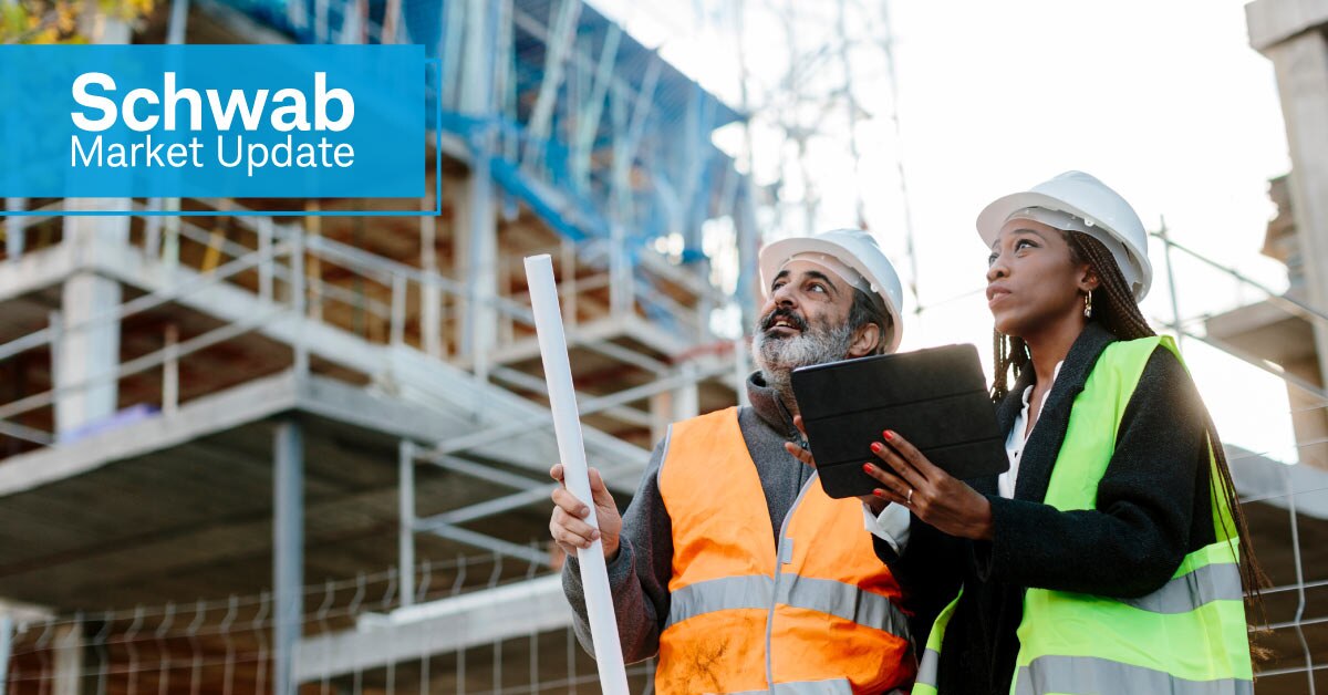 Schwab Market Update: An engineer consults with a construction worker on a building site.