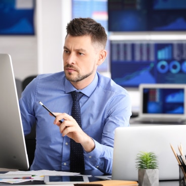 A man sitting at a computer in a suit and tie.