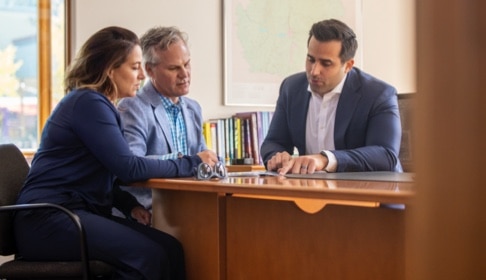 Financial consultant sitting at a desk offering guidance to two people 