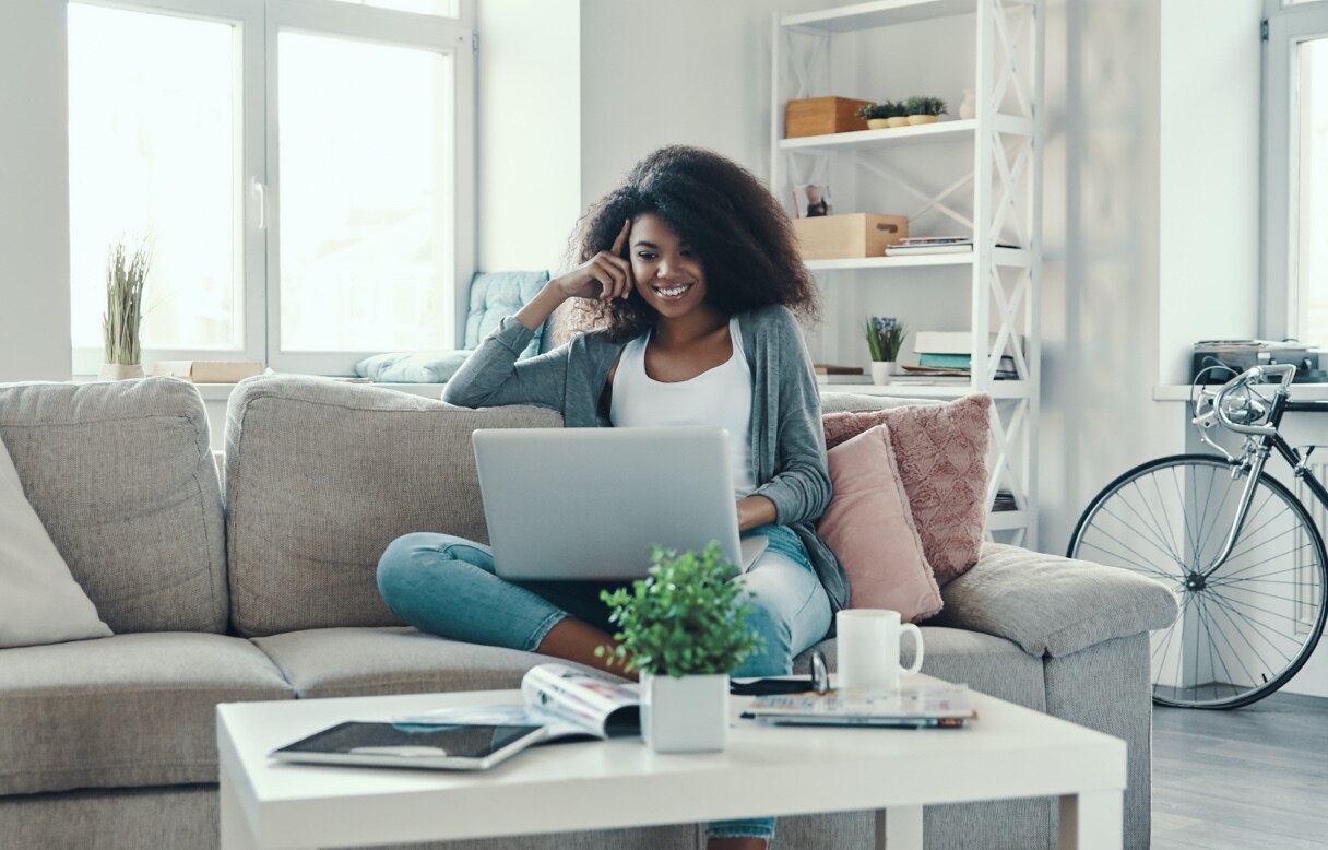 Female options trader using a laptop on a couch